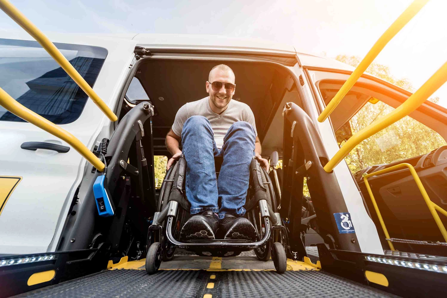 Handicap Fahrzeuge GmbH - Ein Mann im Rollstuhl auf einem Lift eines Fahrzeugs für Menschen mit Behinderungen